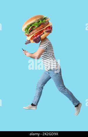Springender Mann mit leckerem Burger statt Kopf und Smartphone auf hellblauem Hintergrund Stockfoto