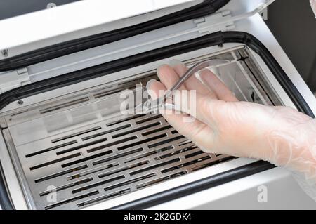 Hand mit Maniküre und Pediküre nach der Sterilisation und Desinfektion in trockenem Heißluftsterilisator. Stockfoto