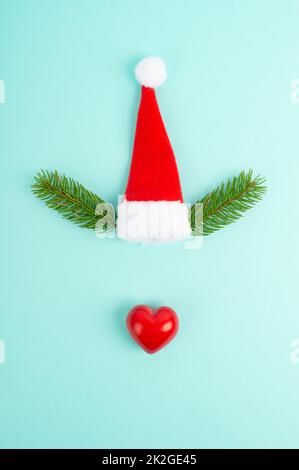 Gesicht eines Rentiers mit roter Herznase, Tannengeweih und Weihnachtsmannhut, fröhliche weihnachtskarte Stockfoto