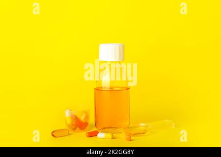 Flasche Hustensirup, Tasse, Löffel und Pillen auf gelbem Hintergrund Stockfoto
