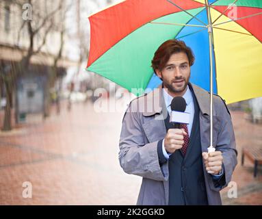 Und es sieht aus wie Regen heute Leute. Ein lächelnder Wettermann, der aus einem städtischen Gebiet berichtet. Stockfoto