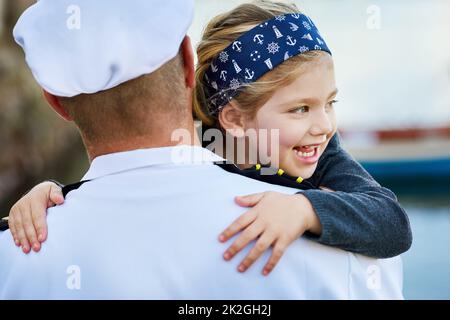 Freut sich, ihren Dhat wieder zu Hause zu haben. Rückansicht eines Vaters in einer Marineinuniform, der sein glückliches kleines Mädchen umarmt. Stockfoto