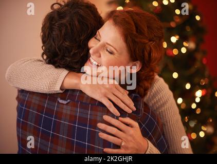 Frohe Weihnachten, Baby. Kurzer Screenshot eines anhänglichen jungen Paares, das sich zu Weihnachten umarmt. Stockfoto