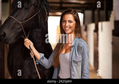 Hey, Mädchen, warum. Porträt einer jungen Frau in einem Stall mit ihrem Pferd. Stockfoto