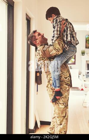 Schau, wie groß du geworden bist. Aufnahme eines kleinen Jungen, der seinen Vater von der Armee nach Hause begrüßt. Stockfoto