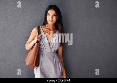 Ich habe alles, was ich brauche, in meiner Handtasche. Studioporträt einer attraktiven jungen Frau, die ihre Handtasche hält. Stockfoto