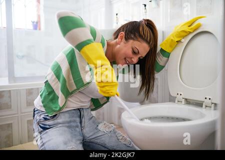 Schrubben und Reinigen. Aufnahme einer jungen Frau, die eine Toilette im Badezimmer putzt. Stockfoto