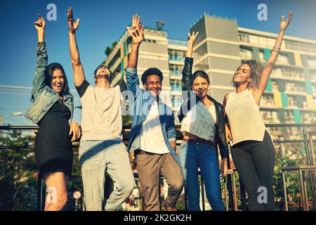 Mit solchen Freunden ist das Leben besser. Eine kurze Aufnahme einer Gruppe junger Freunde, die den Tag draußen auf einem Dach verbringen. Stockfoto