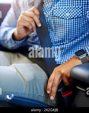 Schnallen Sie sich an und bewahren Sie sie sicher auf. Ausgeschnittene Aufnahme eines nicht identifizierbaren Mannes, der seinen Sicherheitsgurt in einem Fahrzeug festlegte. Stockfoto