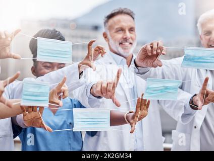 Alles, was Sie tun müssen, ist eine Maske zu tragen. Aufnahme einer Gruppe von Ärzten, die in der Stadt Masken halten. Stockfoto