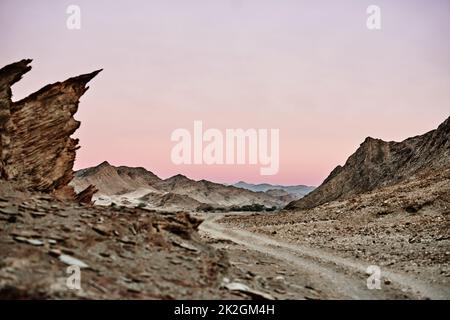 Durch eine jenseitige Landschaft. Aufnahme einer unbefestigten Straße, die durch raues Gelände führt. Stockfoto