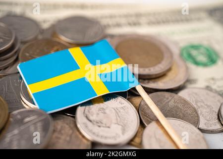 Stapel von Münzen mit Schwedenflagge auf US-amerikanischen Dollar-Banknoten. Stockfoto