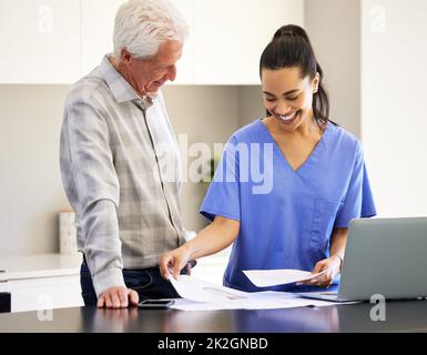 Vielen Dank, dass Sie mir dabei geholfen haben. Aufnahme einer Krankenschwester, die mit ihrer älteren Patientin über den Papierkram ging. Stockfoto