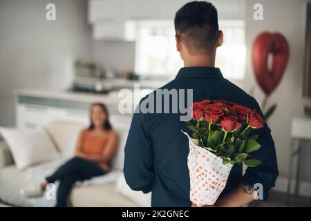 Ich habe eine Überraschung für Sie bekommen. Aufnahme eines jungen Mannes, der seine Frau zu Hause mit Blumen überraschte. Stockfoto