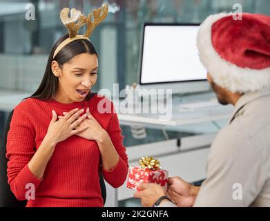 Für meinen Lieblingskollegen. Aufnahme eines jungen Geschäftsmannes und einer Geschäftsfrau, die in einem modernen Büro Weihnachtsgeschenke austauschten. Stockfoto