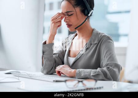 Ich glaube, ich brauche eine Pause. Aufnahme einer jungen Geschäftsfrau, die mit Kopfschmerzen in einem Callcenter arbeitet. Stockfoto