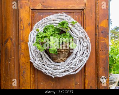 Angelsberg, Schweden - 28. Mai 2022: Türgirlande aus weißen Zweigen mit Blumentopf in der Mitte Stockfoto