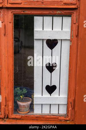 Angelsberg, Schweden - 28. Mai 2022: Traditionelle weiße Fensterläden auf alten Häuschen mit Herzen Stockfoto