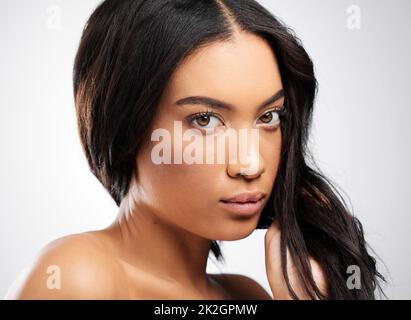 Du musst deine Haarpflege ernst nehmen. Beschnittenes Porträt einer attraktiven jungen Frau, die im Studio vor grauem Hintergrund posiert. Stockfoto