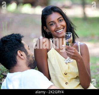 Er macht mein Herz glücklich. Aufnahme einer jungen Frau, die bei einem Date im Park Champagner trinkt. Stockfoto