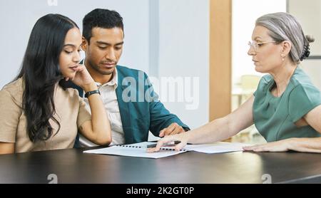 So sehen Ihre Finanzen aus. Eine kleine Aufnahme eines jungen Paares, das während eines Treffens mit seinem Finanzberater über einige Formalitäten ging. Stockfoto