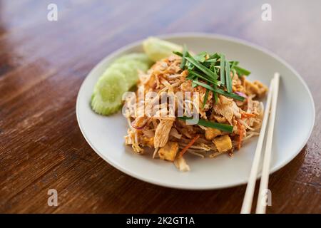 Eine Hühnerkühe kam gleich hoch. Nahaufnahme des chinesischen Essens auf einem Teller auf einem Holztisch. Stockfoto