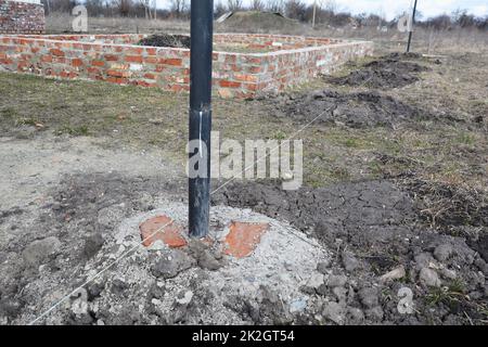 Graben von Löchern für Zaun Metallsäulen Betonfundament Stockfoto