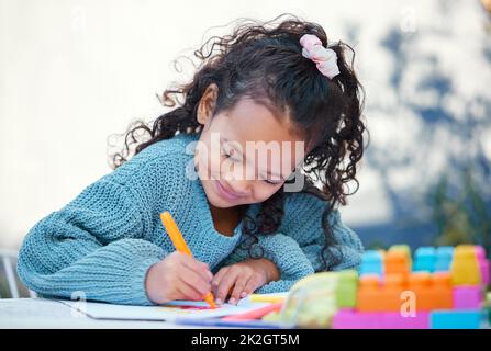 Hausaufgaben im Freien zu machen, ist viel besser. Aufnahme eines kleinen Mädchens, das in ihrem Hof Hausaufgaben macht. Stockfoto