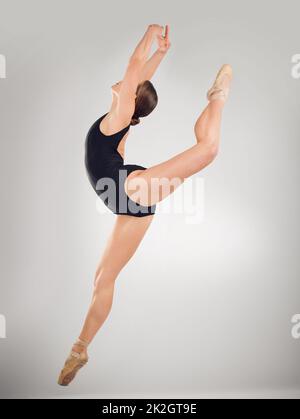 Eine perfekte Form ist erforderlich. Ganzkörperaufnahme einer attraktiven jungen Balletttänzerin im Studio vor grauem Hintergrund. Stockfoto