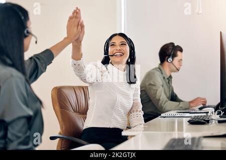 Heres zu machen alle großen Verkäufe heute. Aufnahme einer jungen Callcenter-Mitarbeiterin, die ihrem Kollegen in einem Büro eine hohe Fünftel gab. Stockfoto