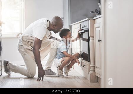 Es macht so viel Spaß, alle Zutaten zu mischen. Aufnahme eines Vaters und eines Sohnes, der in der Küche neben dem Ofen steht. Stockfoto