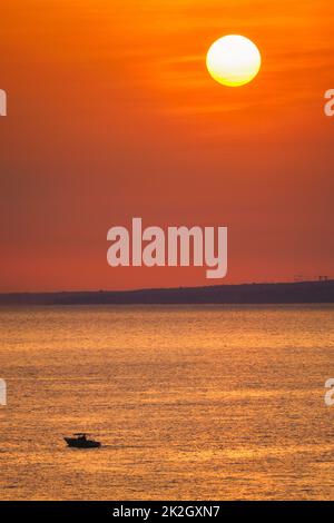 Kleines Fischerboot im Meer bei Sonnenuntergang Stockfoto