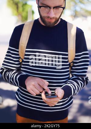 Der Inbegriff von Geek trifft auf Hip trifft auf den modernen Hipster. Ein hübscher junger Hipster im Freien, während er eine Brille trägt. Stockfoto