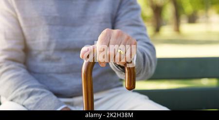 Schließlich werden Sie Hilfe von einem Stock benötigen. Nahaufnahme eines nicht erkennbaren älteren Mannes, der sich draußen an seinem Spazierstock festhält. Stockfoto