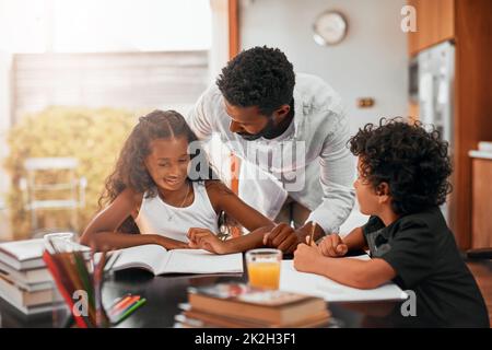 Legen Sie einen regelmäßigen Zeitplan für die Durchführung von Hausaufgaben fest. Aufnahme eines Vaters, der seinen Kindern bei ihren Hausaufgaben hilft. Stockfoto