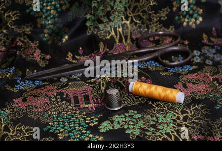 Gelbes Faden und Kaugummi auf klassischer chinesischer schwarzer Seide Stockfoto