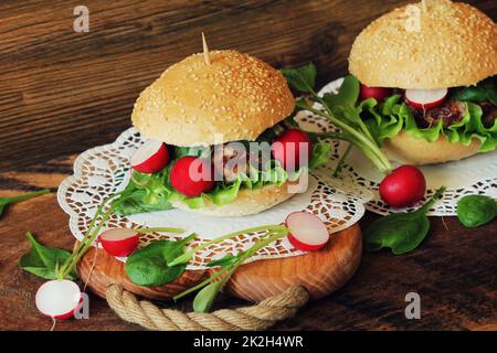 Hausgemachte Burger mit Rindfleisch, Radieschen, Salat, auf hölzernen Hintergrund serviert. Stockfoto