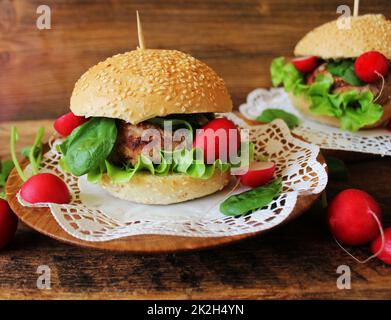 Hausgemachte Burger mit Rindfleisch, Radieschen, Salat, auf hölzernen Hintergrund serviert. Stockfoto