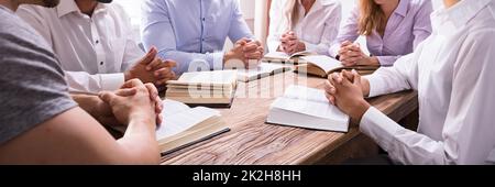 Gruppe von Jungen multiethnischen Menschen Lesen der Bibel über Holz- Schreibtisch Stockfoto