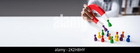 Geschäftsmann, Der Figuren Der Bauern Anzieht, Mit Horseshoe Magnet Stockfoto