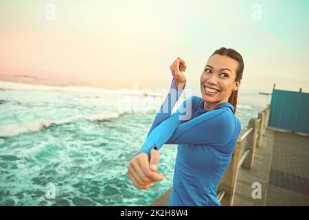 Überprüfen Sie diese Ziele nacheinander. Aufnahme einer sportlichen jungen Frau, die sich vor ihrem Lauf dehnt. Stockfoto