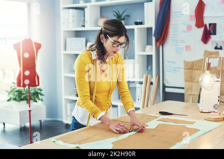 Vorbereitung ist der Schlüssel zum Erfolg. Eine kurze Aufnahme einer attraktiven jungen Modedesignerin in ihrer Werkstatt. Stockfoto