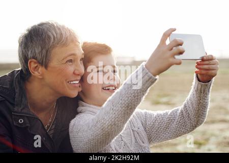 Pose für die Oma der Kamera. Aufnahme eines entzückenden kleinen Jungen, der ein Selfie mit seiner Großmutter im Freien gemacht hat. Stockfoto