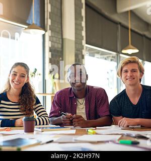 Willkommen bei unserem Studienplatz. Porträt einer Gruppe glücklicher Studenten, die in einem Café eine Studiensitzung machen. Stockfoto