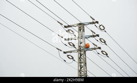 Nahaufnahme des oberen Teils eines Stromverteilungspylons und von Stromleitungen in niedriger Perspektive Stockfoto