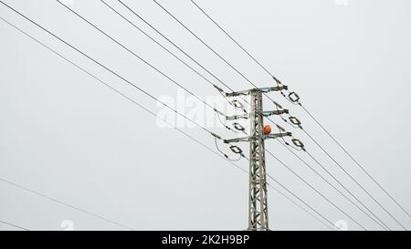 Nahaufnahme des oberen Teils eines Stromverteilungspylons und von Stromleitungen in niedriger Perspektive Stockfoto