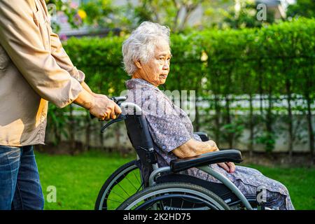 Asiatische ältere Frau Behinderung Patient sitzt auf Rollstuhl im Park, medizinisches Konzept. Stockfoto