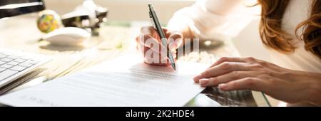 Die Hand einer Geschäftsfrau, die einen Vertrag mit Pen unterzeichnet Stockfoto