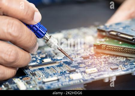 Techniker, der die Leiterplatteninnenseite mit einem Lötkolben repariert. Integrierter Schaltkreis. Das Konzept von Daten, Hardware, Techniker und Technologie. Stockfoto