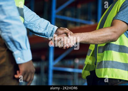 Stolz darauf, einen zuverlässigen Partner wie Sie zu haben. Aufnahme von zwei Bauherren, die sich auf einer Baustelle die Hände schüttelten. Stockfoto